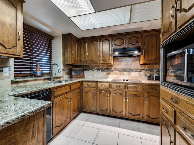 713 Bordner Dr, Lancaster, TX 75146 - kitchen with under cabinet range hood, light tile patterned flooring, decorative backsplash, black appliances, and light stone countertops