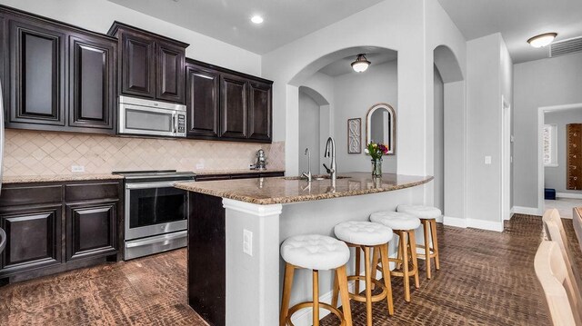 3513 Holly Rd, Melissa, TX 75454 - kitchen with appliances with stainless steel finishes, a kitchen breakfast bar, tasteful backsplash, and stone countertops