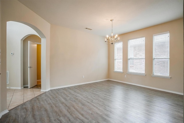 5831 Melanie Ct, Fort Worth, TX 76131 - empty room featuring light wood-type flooring, a chandelier, and arched walkways
