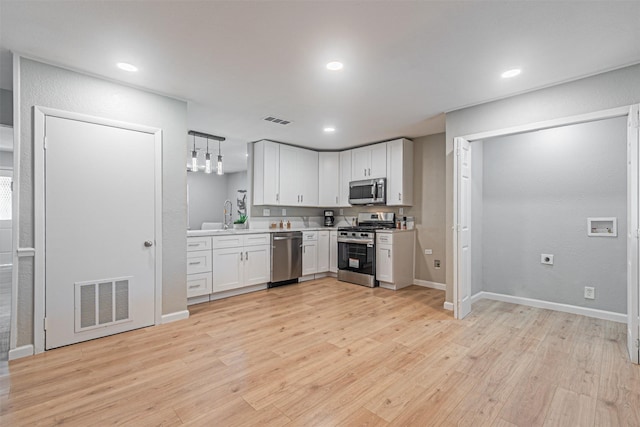 5307 Kelly Elliott, Arlington, TX 76017 - kitchen with appliances with stainless steel finishes, light countertops, light wood finished floors, white cabinetry, and recessed lighting