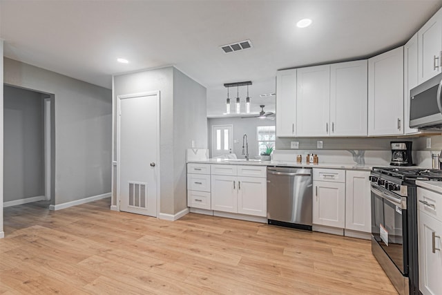 5307 Kelly Elliott, Arlington, TX 76017 - kitchen with stainless steel appliances, light countertops, light wood-style flooring, white cabinets, and hanging light fixtures