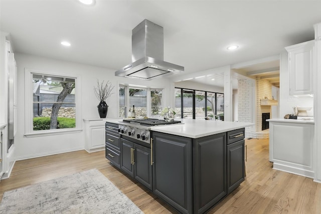 208 Rockwood Park Dr, Fort Worth, TX 76107 - kitchen featuring island exhaust hood, stainless steel gas stovetop, white cabinets, light countertops, and light wood finished floors