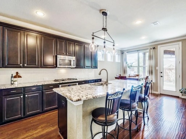 301 Komron Ct, Prosper, TX 75078 - kitchen featuring appliances with stainless steel finishes, crown molding, light stone countertops, dark wood-style floors, and a breakfast bar area