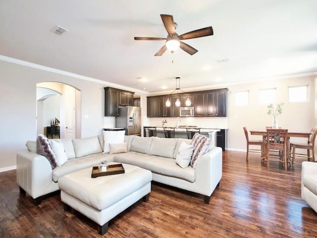 301 Komron Ct, Prosper, TX 75078 - living area featuring crown molding, ceiling fan, arched walkways, and dark wood-style flooring
