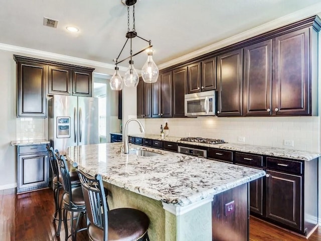301 Komron Ct, Prosper, TX 75078 - kitchen with appliances with stainless steel finishes, light stone countertops, dark brown cabinets, ornamental molding, and recessed lighting