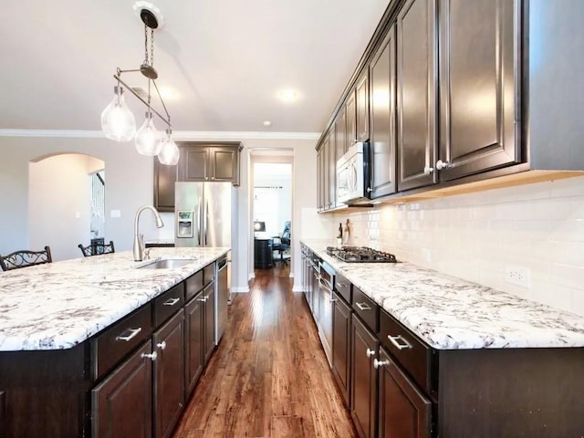 301 Komron Ct, Prosper, TX 75078 - kitchen with stainless steel appliances, dark brown cabinets, arched walkways, ornamental molding, and dark wood finished floors