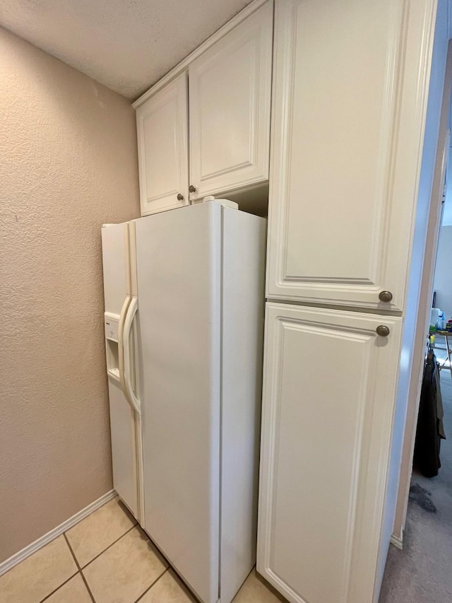 817 W Harwood Rd Unit B, Hurst, TX 76054 - kitchen with white refrigerator with ice dispenser, a textured wall, light tile patterned floors, and white cabinetry