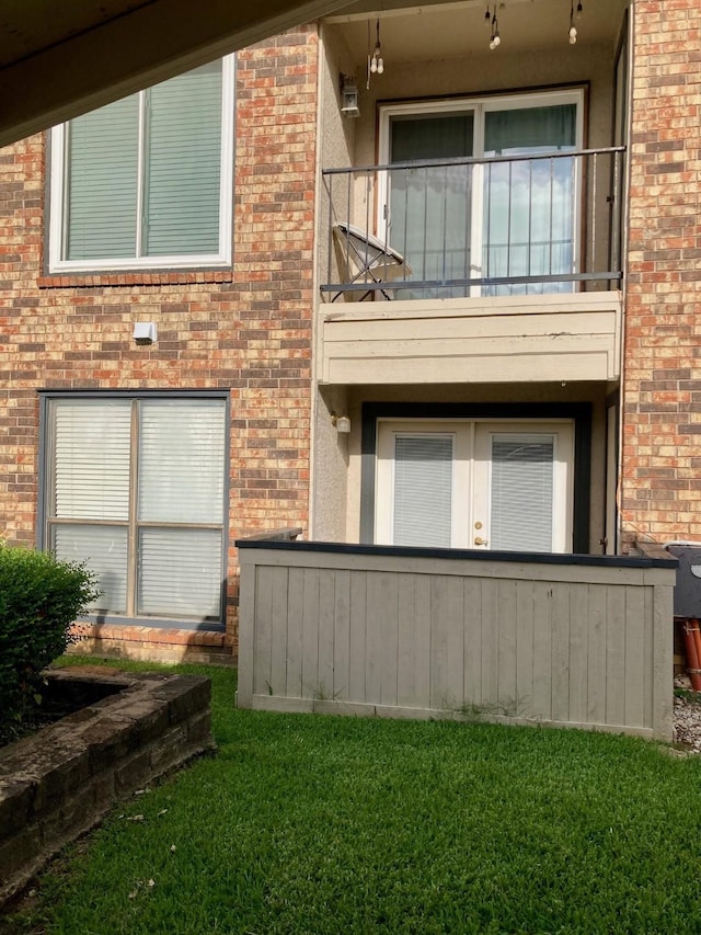 817 W Harwood Rd Unit B, Hurst, TX 76054 - back of property featuring a balcony, brick siding, and a yard