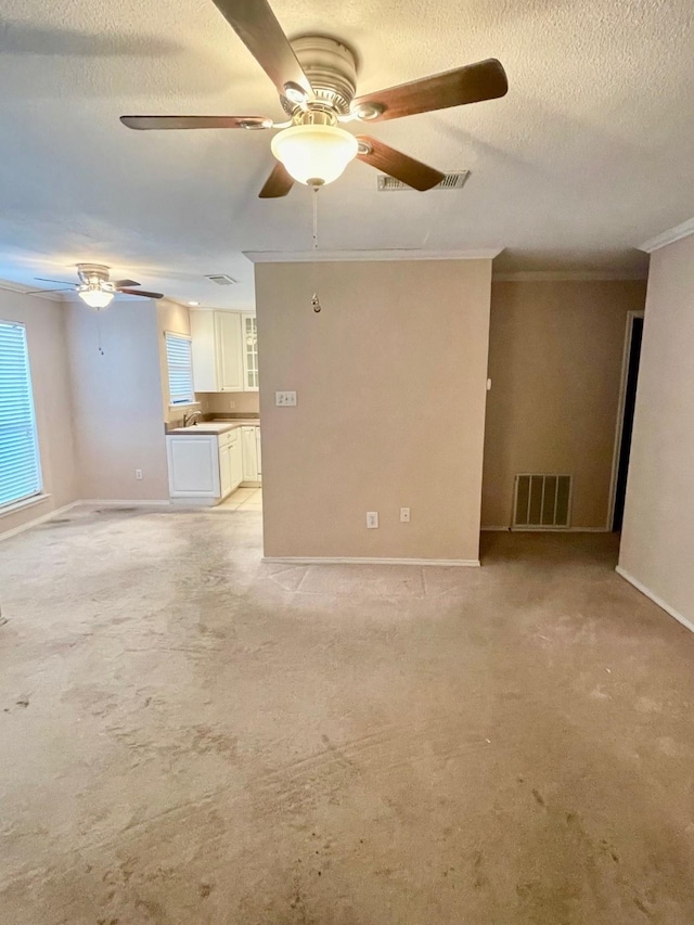 817 W Harwood Rd Unit B, Hurst, TX 76054 - unfurnished living room featuring a ceiling fan, crown molding, a textured ceiling, and light colored carpet