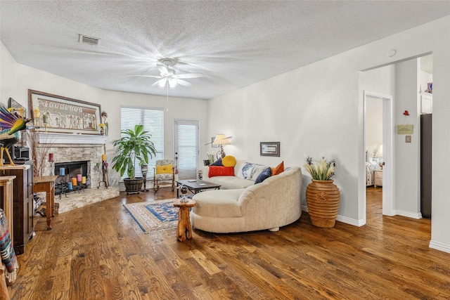 7210 Mercurys Rd, Rowlett, TX 75089 - living room with a ceiling fan, wood finished floors, a textured ceiling, and a stone fireplace
