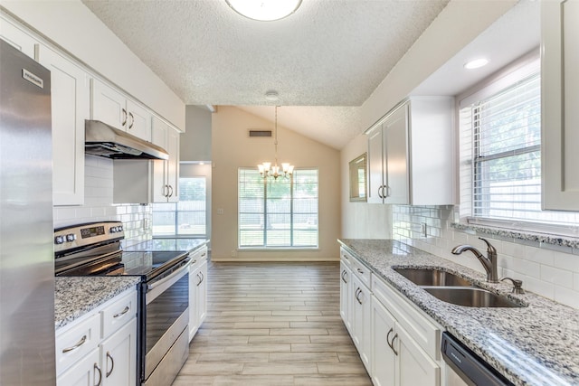 1704 Edge Hill Rd, Benbrook, TX 76126 - kitchen with stainless steel appliances, under cabinet range hood, a textured ceiling, vaulted ceiling, and white cabinetry