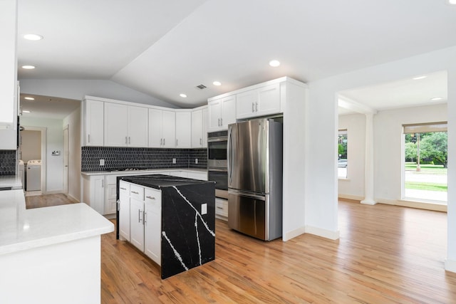 5710 Forest Ln, Dallas, TX 75230 - kitchen featuring appliances with stainless steel finishes, washer / dryer, light wood-style floors, backsplash, and white cabinets
