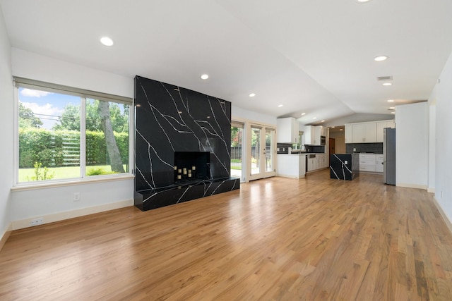 5710 Forest Ln, Dallas, TX 75230 - unfurnished living room with light wood finished floors, lofted ceiling, recessed lighting, and a premium fireplace