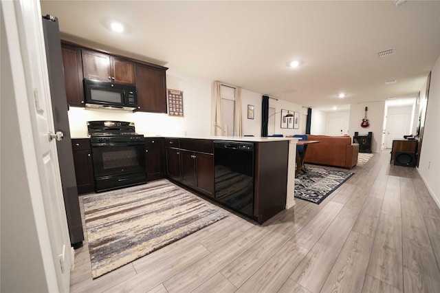 3117 Harper St, Little Elm, TX 75068 - kitchen with black appliances, open floor plan, light wood-style flooring, a peninsula, and dark brown cabinetry