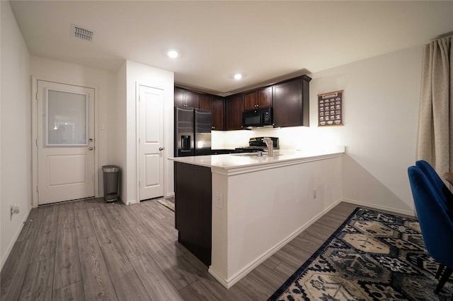 3117 Harper St, Little Elm, TX 75068 - kitchen featuring black microwave, stainless steel fridge, dark brown cabinetry, wood finished floors, and a peninsula