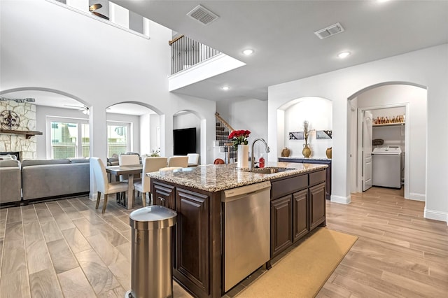 303 Hidden Cove Dr, Ponder, TX 76259 - kitchen with stainless steel dishwasher, washer / dryer, open floor plan, dark brown cabinets, and light stone counters