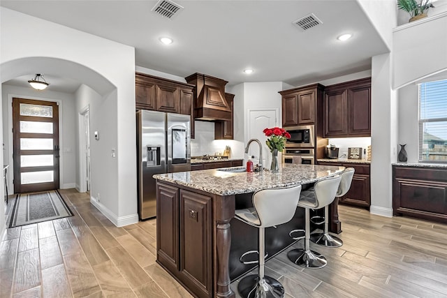 303 Hidden Cove Dr, Ponder, TX 76259 - kitchen with stainless steel appliances, arched walkways, light wood-type flooring, a kitchen bar, and recessed lighting