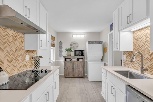 10763 Villager Unit A, Dallas, TX 75230 - kitchen with under cabinet range hood, black appliances, stacked washer / drying machine, and tasteful backsplash
