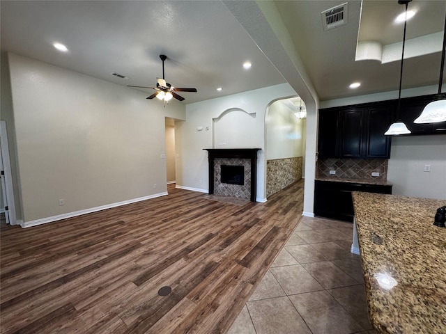 205 Boardwalk Ave, Waxahachie, TX 75165 - kitchen with ceiling fan, dark cabinetry, dark wood-style floors, light stone counters, and hanging light fixtures
