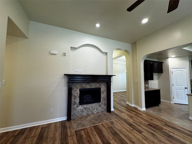 205 Boardwalk Ave, Waxahachie, TX 75165 - unfurnished living room featuring ceiling fan, dark wood finished floors, a tiled fireplace, arched walkways, and recessed lighting