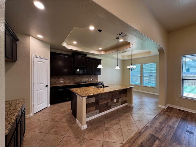 205 Boardwalk Ave, Waxahachie, TX 75165 - kitchen featuring black appliances, a raised ceiling, backsplash, stone counters, and a chandelier
