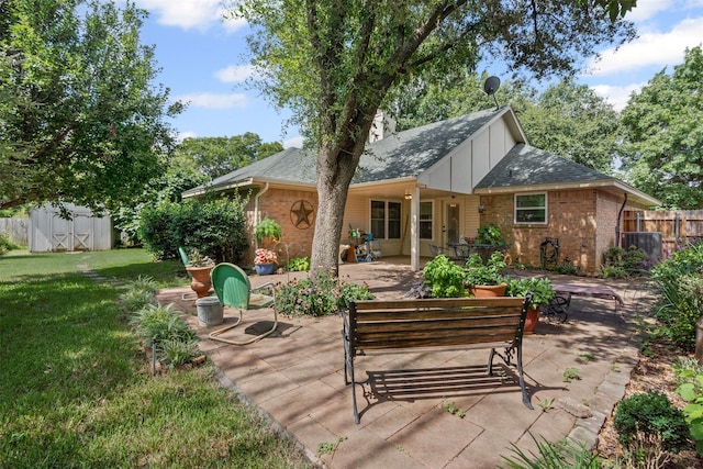 9013 Topperwind Ct, Fort Worth, TX 76134 - back of property with brick siding, a patio area, a shingled roof, board and batten siding, and a storage unit