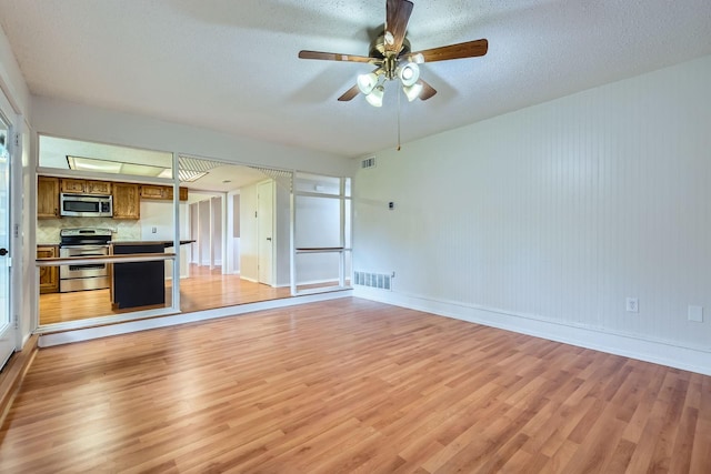 902 Via Valencia, Mesquite, TX 75150 - unfurnished living room featuring light wood-style flooring, a ceiling fan, and a textured ceiling