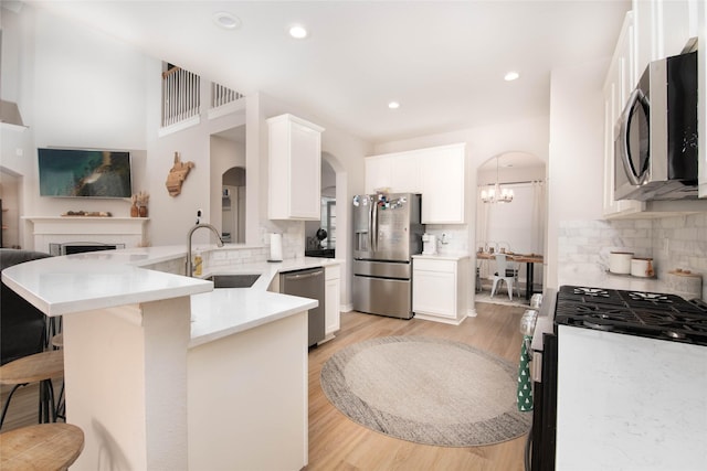 12720 Outlook Ave, Fort Worth, TX 76244 - kitchen featuring stainless steel appliances, arched walkways, tasteful backsplash, a breakfast bar area, and a peninsula