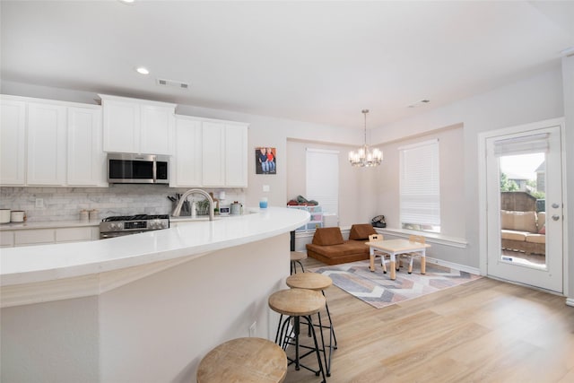 12720 Outlook Ave, Fort Worth, TX 76244 - kitchen featuring stainless steel appliances, backsplash, light wood-style floors, a chandelier, and white cabinets