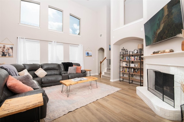 12720 Outlook Ave, Fort Worth, TX 76244 - living area with arched walkways, wood finished floors, a fireplace, a high ceiling, and stairway