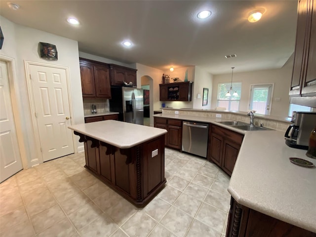 740 Bridgeport Ln, Prosper, TX 75078 - kitchen with stainless steel appliances, arched walkways, light countertops, dark brown cabinetry, and a breakfast bar area