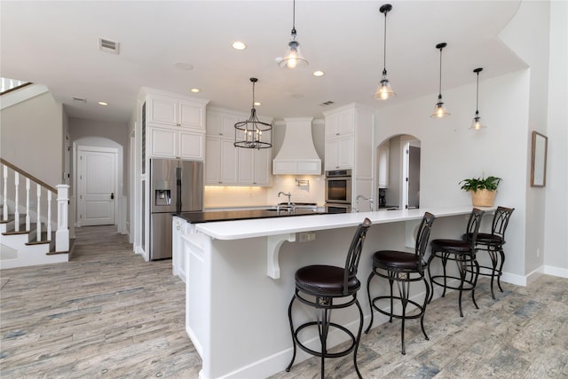 100 Redtail Hawk Dr, Aledo, TX 76008 - kitchen with stainless steel appliances, arched walkways, custom range hood, light wood finished floors, and recessed lighting