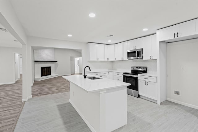6401 Simmons Rd, North Richland Hills, TX 76182 - kitchen with stainless steel appliances, light countertops, white cabinetry, light wood-style floors, and a fireplace