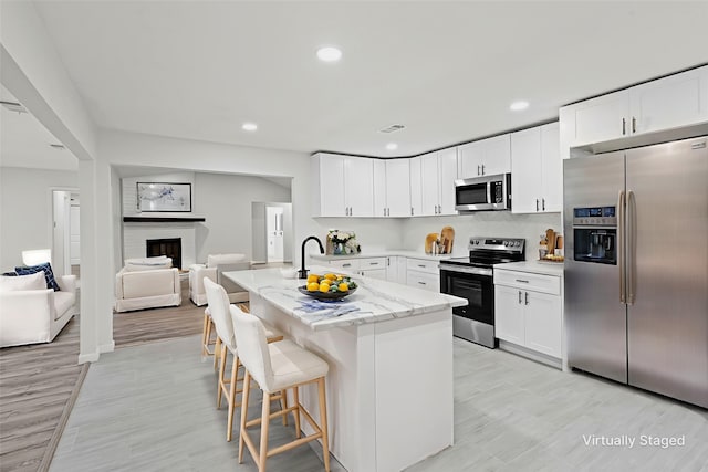 6401 Simmons Rd, North Richland Hills, TX 76182 - kitchen featuring stainless steel appliances, a kitchen bar, open floor plan, white cabinets, and light stone counters