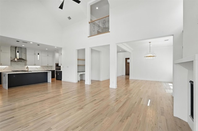 13868 Dorset Ln, Frisco, TX 75035 - unfurnished living room featuring a chandelier, ceiling fan, a towering ceiling, light wood-style floors, and recessed lighting