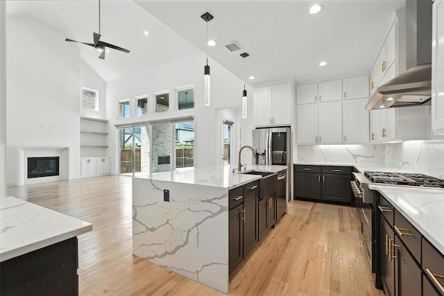 13868 Dorset Ln, Frisco, TX 75035 - kitchen featuring appliances with stainless steel finishes, wall chimney range hood, light wood finished floors, high vaulted ceiling, and a ceiling fan