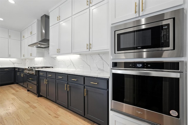 13868 Dorset Ln, Frisco, TX 75035 - kitchen featuring appliances with stainless steel finishes, wall chimney range hood, light wood-style floors, white cabinetry, and recessed lighting