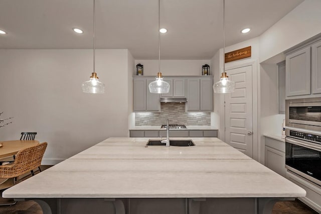 778 Corner Post Path, Celina, TX 75009 - kitchen with appliances with stainless steel finishes, gray cabinetry, a kitchen breakfast bar, under cabinet range hood, and backsplash