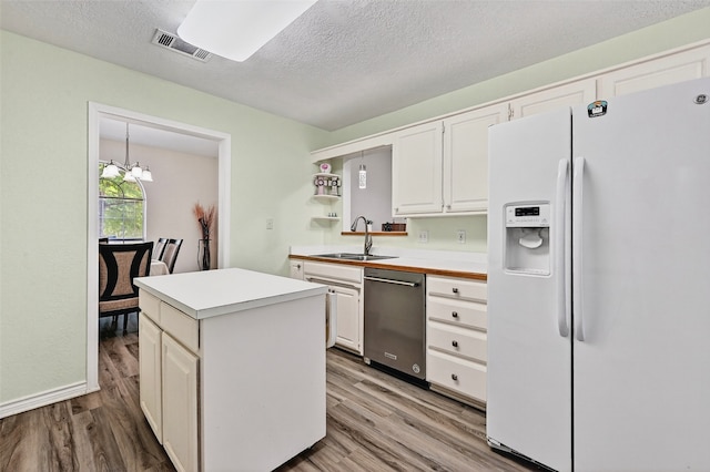 2107 Meadows Cir, Sherman, TX 75092 - kitchen with white refrigerator with ice dispenser, dishwasher, light countertops, wood finished floors, and a textured ceiling