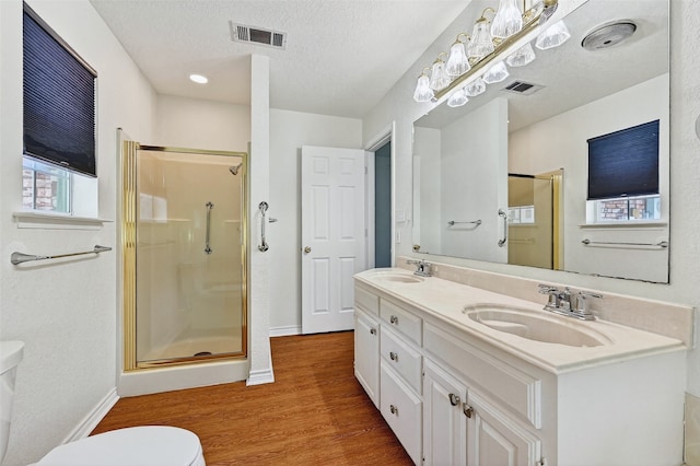 2107 Meadows Cir, Sherman, TX 75092 - bathroom with wood finished floors, a shower stall, double vanity, and a textured ceiling
