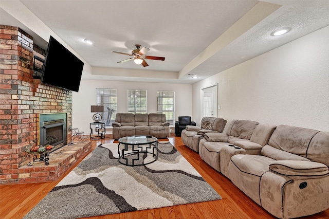 2107 Meadows Cir, Sherman, TX 75092 - living room with a ceiling fan, wood finished floors, a brick fireplace, and a tray ceiling
