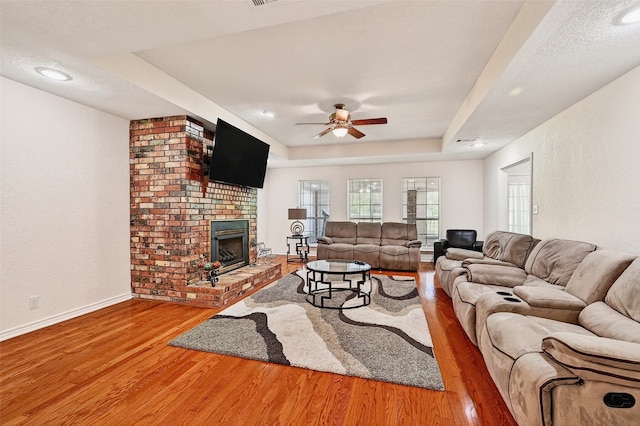 2107 Meadows Cir, Sherman, TX 75092 - living area featuring wood finished floors, a ceiling fan, a brick fireplace, a raised ceiling, and recessed lighting