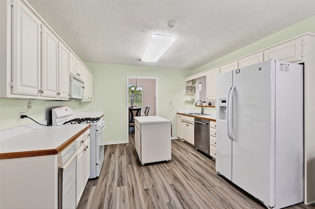 2107 Meadows Cir, Sherman, TX 75092 - kitchen featuring white appliances, white cabinets, a textured ceiling, light wood finished floors, and light countertops