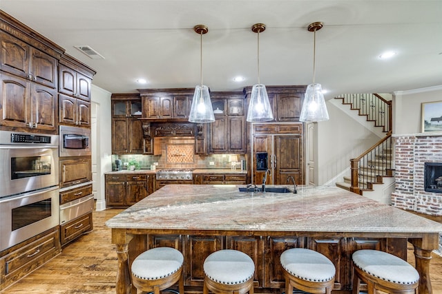 2521 Fair Oaks Ln, Prosper, TX 75078 - kitchen with built in appliances, light wood-type flooring, crown molding, a breakfast bar area, and tasteful backsplash