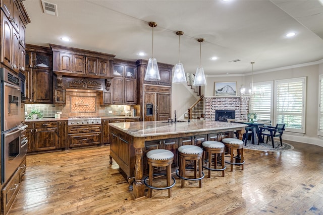 2521 Fair Oaks Ln, Prosper, TX 75078 - kitchen featuring appliances with stainless steel finishes, a kitchen breakfast bar, light wood-style floors, crown molding, and recessed lighting
