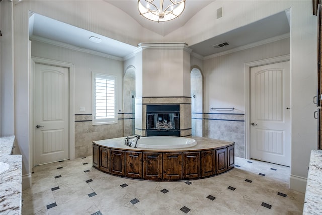 2521 Fair Oaks Ln, Prosper, TX 75078 - bathroom featuring tile walls, a bath, a tiled fireplace, ornamental molding, and a chandelier