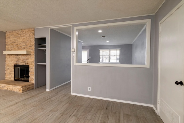 740 Willow St, Hurst, TX 76053 - unfurnished living room with ornamental molding, wood finished floors, a textured ceiling, and a stone fireplace