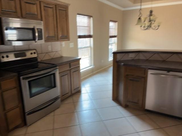 307 W Dormard Ave, Midland, TX 79705 - kitchen with appliances with stainless steel finishes, dark countertops, brown cabinets, ornamental molding, and decorative backsplash