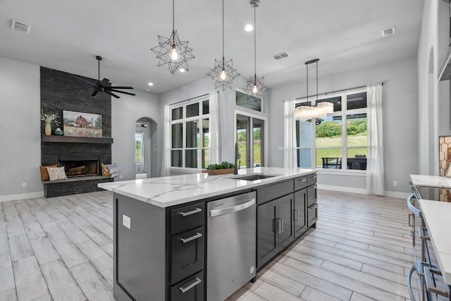 521 Echo Glade Ct, Azle, TX 76020 - kitchen with dishwasher, ceiling fan, wood tiled floors, arched walkways, and a fireplace
