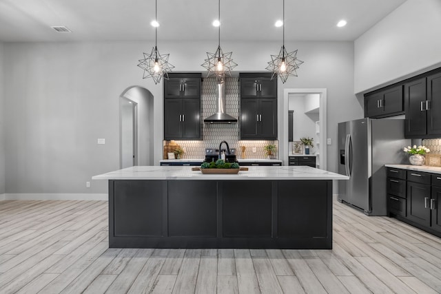 521 Echo Glade Ct, Azle, TX 76020 - kitchen featuring wall chimney exhaust hood, stainless steel fridge, arched walkways, dark cabinetry, and recessed lighting